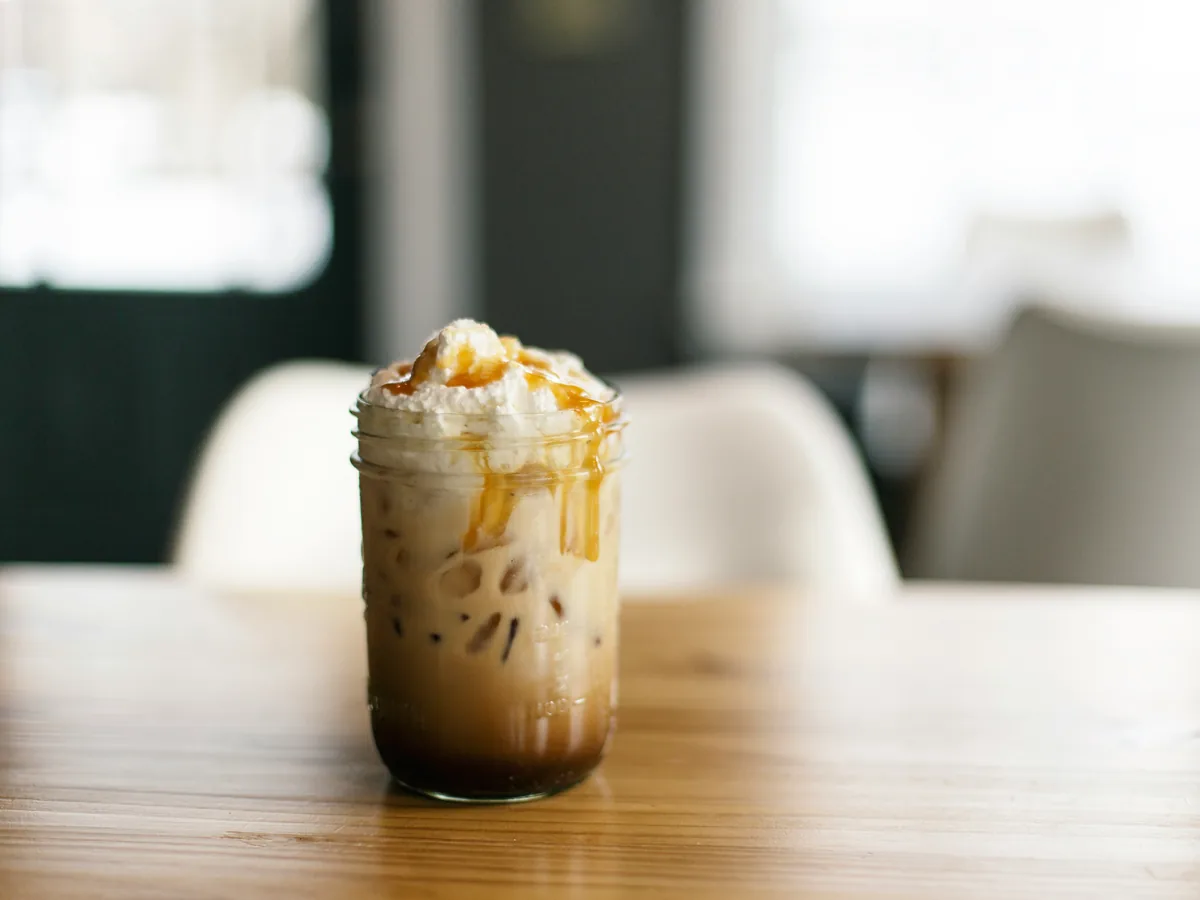 Caramel Frappuccino mit Karamell-Drizzle in einem Glas auf einem Holztisch