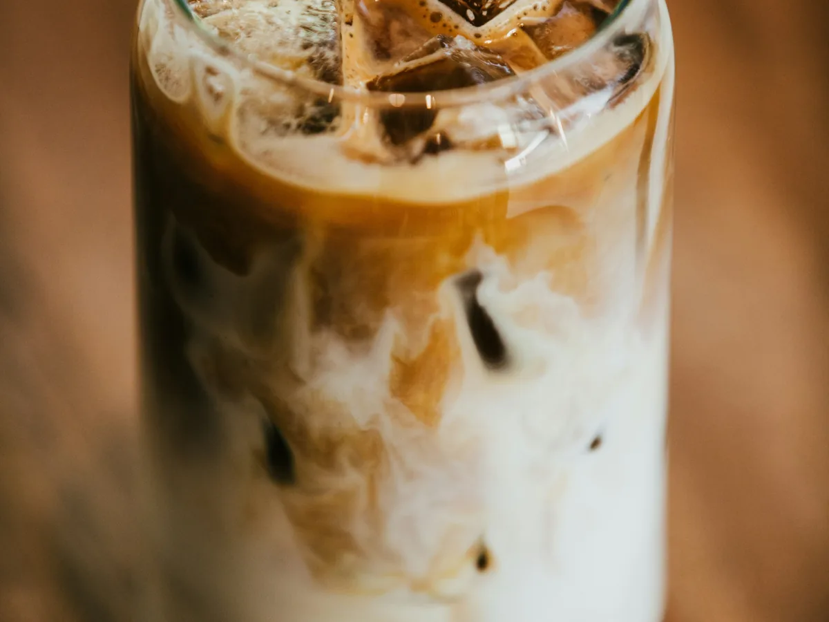 Iced Latte Macchiato mit Eiswürfeln und sichtbaren Milch-Espresso-Schichten im Glas