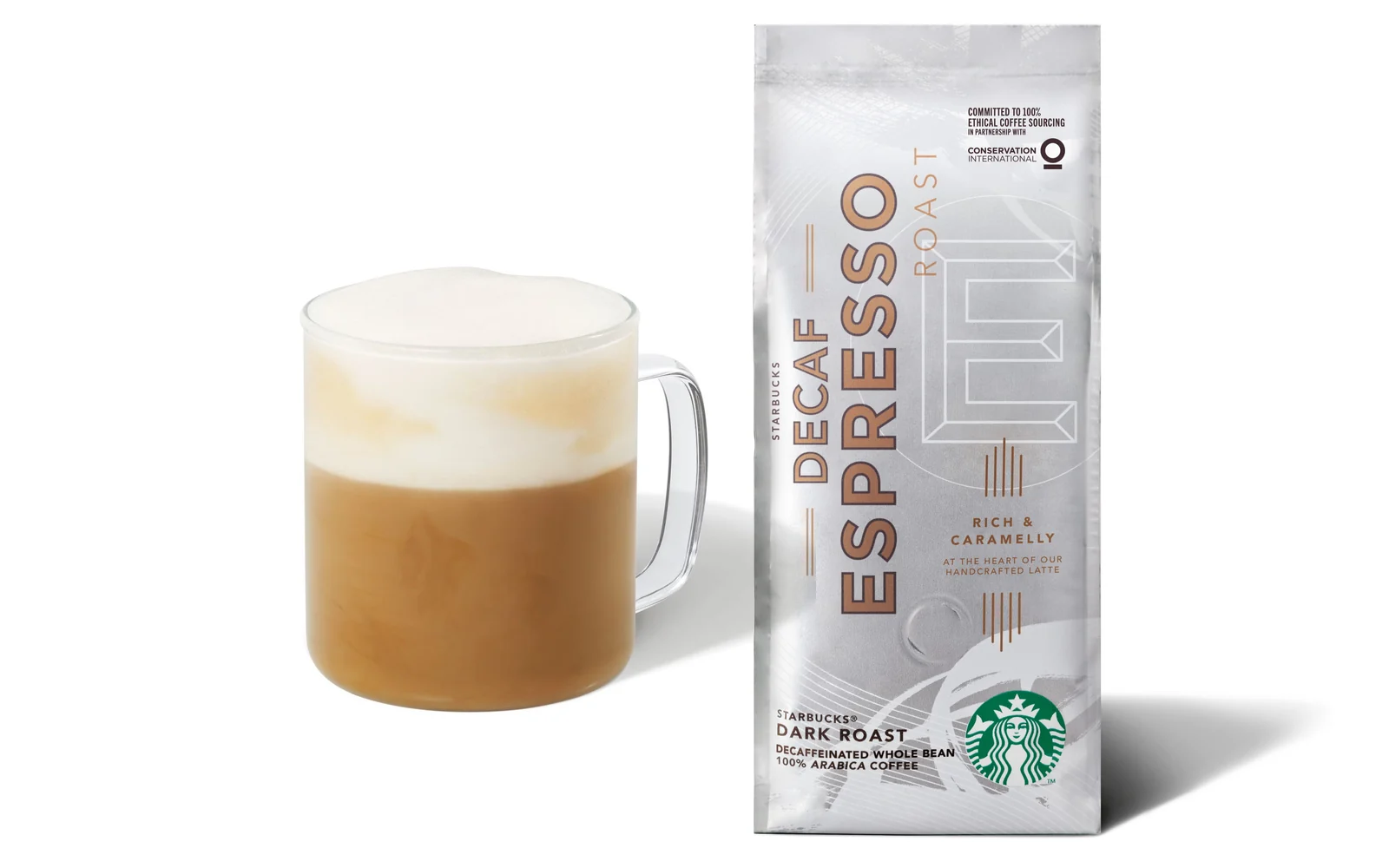 Starbucks Cappuccino im Glasbecher neben einer Packung Starbucks Decaf Espresso Roast vor weißem Hintergrund