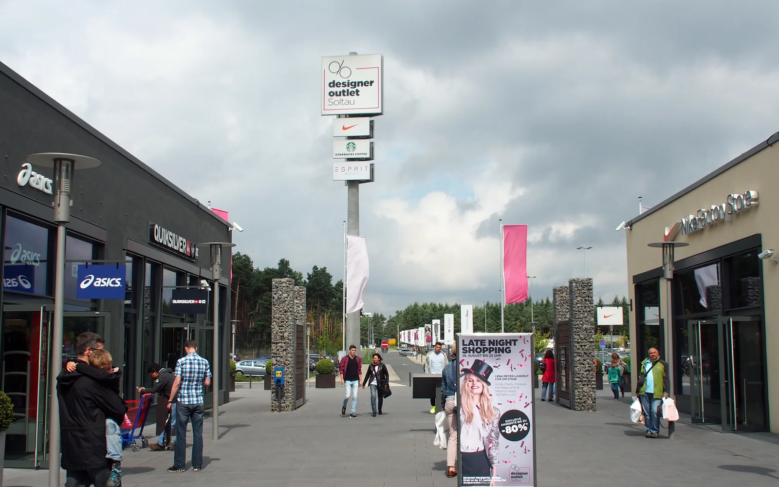 Ladenstraße im Designer Outlet Soltau mit Werbepylon, auf dem Starbucks Coffee neben Nike und Esprit steht (Aufnahme von 2014)